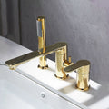 A modern three-hole bathroom faucet set with a polished gold finish, featuring a central spout and two separate handles, mounted on a white sink against a gray tiled wall.
