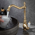 Gold faucet pouring water into a sink with a dark stone background