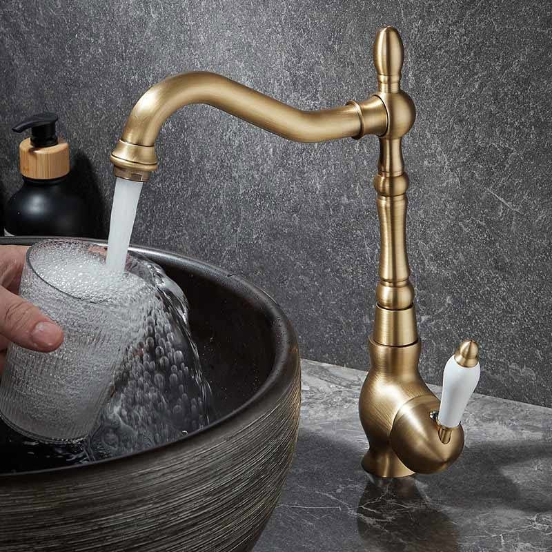 Gold faucet pouring water into a sink with a dark stone background
