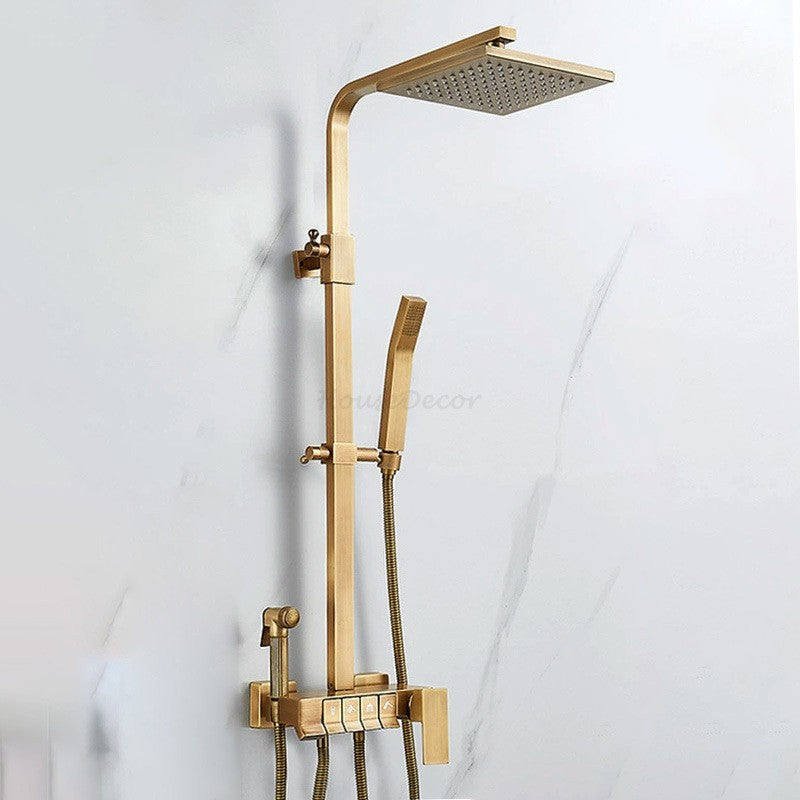 Gold-finished rain shower system with a handheld shower head, mounted on a white marble-look wall.