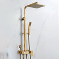 Gold-finished rain shower system with a handheld shower head, mounted on a white marble-look wall.